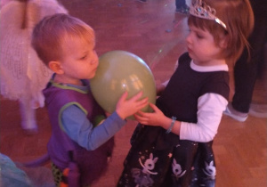 .Dziewczynka i chłopiec tańczą z balonem